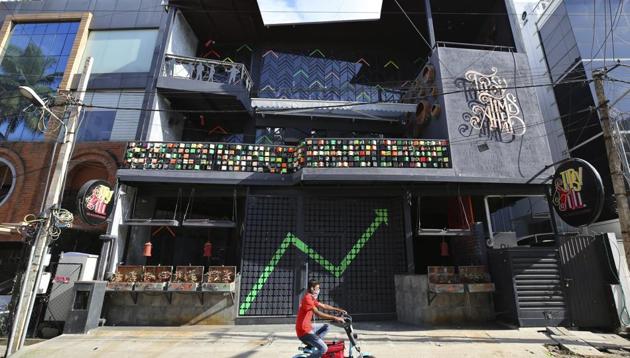 A motorist drives past a famous bar and restaurant closed due to pandemic in Bengaluru, India. Fitch Ratings raised India’s GDP forecast to -9.4 per cent in the current fiscal year to March 2021 from a previously projected contraction of 10.5 per cent.(AP) A motorist drives past a famous bar and restaurant closed due to pandemic in Bengaluru, India. Fitch Ratings raised India’s GDP forecast to -9.4 per cent in the current fiscal year to March 2021 from a previously projected contraction of 10.5 per cent.(AP)