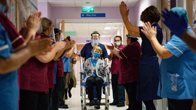 Margaret Keenan (C), 90, is applauded by staff as she returns to her ward after becoming the first person to receive the Pfizer-BioNtech Covid-19 vaccine at University Hospital in Coventry, England, on December 8. Keenan, who turns 91 next week, got the on what public health officials have dubbed “V-Day.” (Jacob King / Pool /AFP)