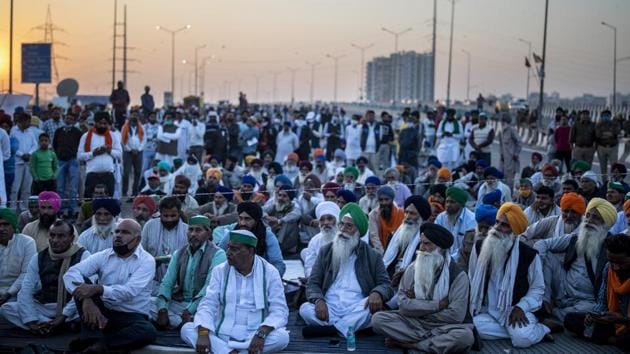 Farmers listen to a speaker on the middle of an expressway at the site of a protest against new farm laws at the Delhi-Uttar Pradesh state border.(AP)