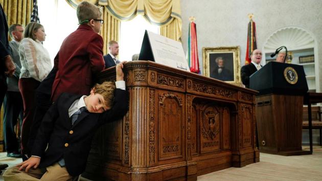 Sammy Olszta, 6, grandson of US Olympic wrestling Gold Medalist and Presidential Medal of Freedom recipient Dan Gable, leans against the Resolute Desk as Gable delivers remarks beside US President Donald Trump during a presentation ceremony inside the Oval Office at the White House in Washington, on December 7. (Tom Brenner / REUTERS) Sammy Olszta, 6, grandson of US Olympic wrestling Gold Medalist and Presidential Medal of Freedom recipient Dan Gable, leans against the Resolute Desk as Gable delivers remarks beside US President Donald Trump during a presentation ceremony inside the Oval Office at the White House in Washington, on December 7. (Tom Brenner / REUTERS)