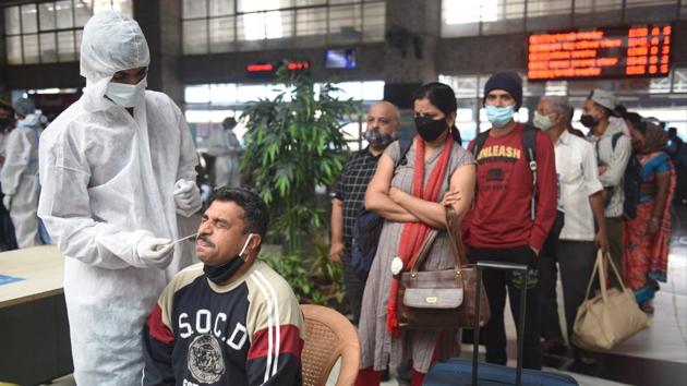 A health worker collects a swab sample of a passenger at Bandra Terminus in Mumbai, on Sunday.(Satish Bate/HT Photo)