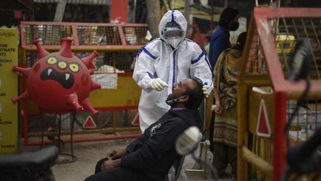 A medical worker collects a swab sample from a man at Lajpat Nagar market in New Delhi on December 11. India’s tests per million population recently crossed the 100,000 mark, with the country performing at least one million tests daily in more than 2,000 Indian Council of Medical Research (ICMR) approved laboratories across the country. (Biplov Bhuyan / HT Photo)