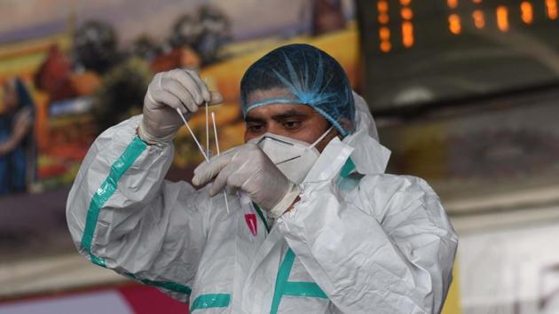 A health care worker in PPE kit works with a swab sample taken from a traveller at New Delhi Railway Station (NDLS) for coronavirus screening, in New Delhi. (Vipin Kumar/HT PHOTO) A health care worker in PPE kit works with a swab sample taken from a traveller at New Delhi Railway Station (NDLS) for coronavirus screening, in New Delhi. (Vipin Kumar/HT PHOTO)