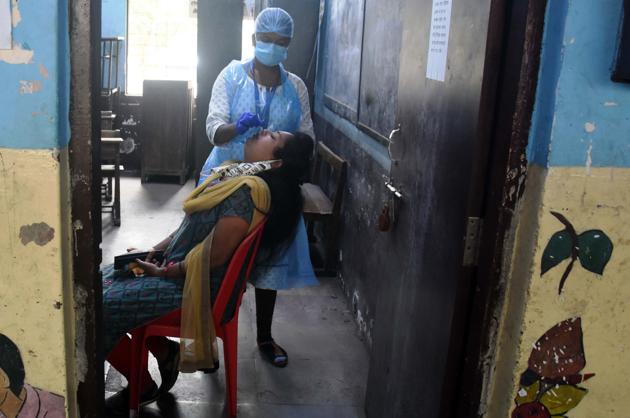 A health worker takes a swab sample of a resident in Thane on Saturday.(Praful Gangurde) A health worker takes a swab sample of a resident in Thane on Saturday.(Praful Gangurde)
