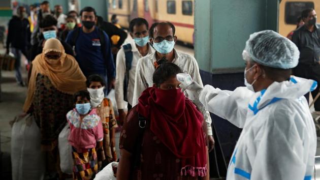 A health worker thermal screens travellers at a railway station in Mumbai on December 11. The rolling average for the past week shows the sustained decline in the daily cases for the six most affected states. The daily new recoveries recorded in the country have been more than the daily cases registered over the last 15 days, HT reported. (Francis Mascarenhas / REUTERS)