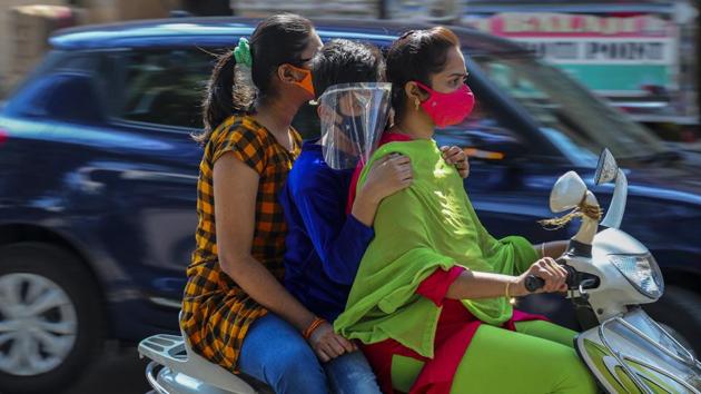 People wearing face masks as a precaution against the coronavirus ride on a scooter in Hyderabad on December 13. The number of active cases went down further to 3,56,546, while 93,57,464 patients have been cured or discharged from the hospitals. Active cases in the country have been declining and are at their lowest in more than 145 days. The last time active cases were at this level was in mid-July. (Mahesh Kumar A. / AP)
