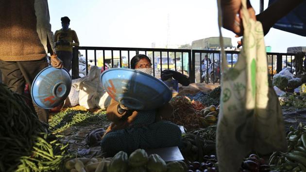 A vegetable vendor wearing a face mask interacts with a buyer at a market in Bengaluru on December 13. India’s present active caseload consists of just 3.66% of the country’s total positive cases. Meanwhile, the recovery rate has reached 94.89%. (Aijaz Rahi / AP)