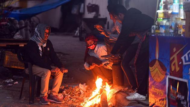 People warm themselves around a bonfire on a cold winter evening at Minto Road, in New Delhi on December 14. Delhi recorded a minimum temperature of 8.4 degrees Celsius on December 14 compared to 11.1 degrees Celsius on the previous day, HT reported. (Raj K Raj / HT Photo) 