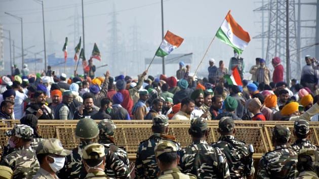 Farmers hold flags as police personnel stand guard behind barricades during protests against new farm laws at Ghazipur (Delhi-UP border) on December 13. Delhi chief minister Arvind Kejriwal on December 14 urged people to observe a one-day fast in solidarity with farmers protesting against the farm laws. He himself is doing so in response to a call given by the farmers protesting at the Singhu border near Delhi. (Sakib Ali / HT Photo) Farmers hold flags as police personnel stand guard behind barricades during protests against new farm laws at Ghazipur (Delhi-UP border) on December 13. Delhi chief minister Arvind Kejriwal on December 14 urged people to observe a one-day fast in solidarity with farmers protesting against the farm laws. He himself is doing so in response to a call given by the farmers protesting at the Singhu border near Delhi. (Sakib Ali / HT Photo)