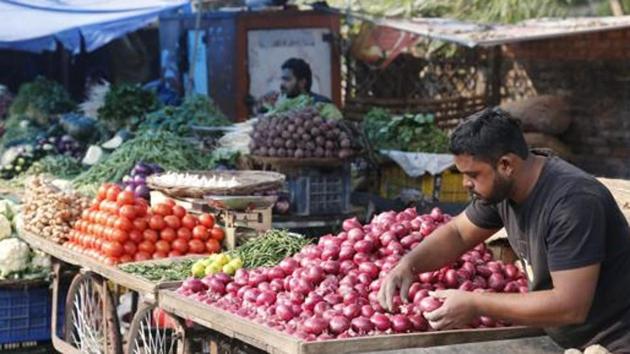 A vegetable vendor awaits customers while arranging onions in his cart at a market in Prayagraj.(AP photo) A vegetable vendor awaits customers while arranging onions in his cart at a market in Prayagraj.(AP photo)