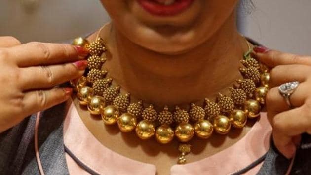 A saleswoman displays a gold necklace to a customer inside a jewellery showroom in Mumbai.(Reuters)