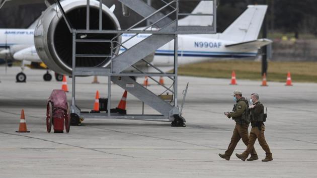 US Marshalls walk on the tarmac Sunday, Dec. 13, 2020, while guarding the first shipment of Pfizer-BioNTech Covid-19 vaccines as they are transferred from a truck to a UPS cargo jet at Capital Region International Airport in Lansing, Mich.(AP)