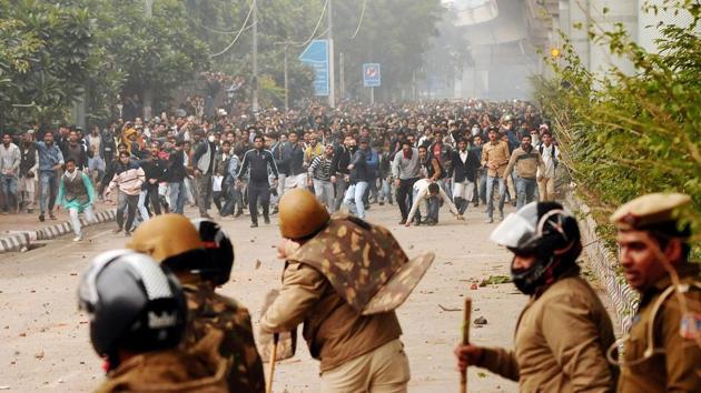 Police personnel pelt stones back as students at Jamia Millia Islamia stage a protest against the CAA on December 13. The violence came two days after protesting students were lathi-charged by police at the university, after which 50 people were detained and large gatherings banned in the area. The Jamia Millia students’ community as well as the teachers’ association distanced themselves from the violence and arson. (HT Photo)