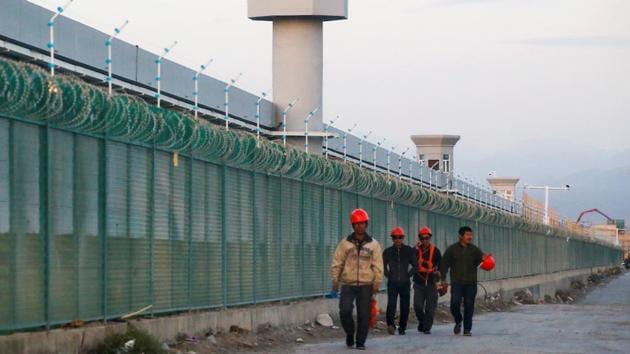 People walk by the perimeter fence of what is officially known as a vocational skills education centre in Dabancheng in Xinjiang Uighur Autonomous Region, China.(REUTERS/ FILE) People walk by the perimeter fence of what is officially known as a vocational skills education centre in Dabancheng in Xinjiang Uighur Autonomous Region, China.(REUTERS/ FILE)