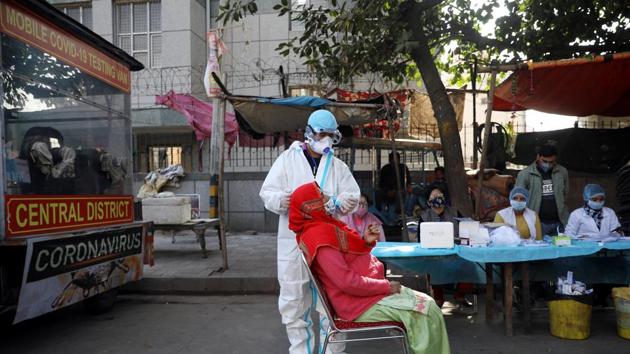A healthcare worker collects a sample from a woman for Covid-19), at a bus depot in New Delhi on December 14.(ANI) A healthcare worker collects a sample from a woman for Covid-19), at a bus depot in New Delhi on December 14.(ANI)
