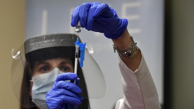 Gina Harper, clinical coordinator with the pharmacy, measures out the exact amount of the Covid-19 vaccine for a dose before it is administered to the first patients in Colorado at UCHealth Poudre Valley Hospital, Monday, Dec. 14, 2020, in Fort Collins, Colo. (Helen H. Richardson/The Denver Post via AP)