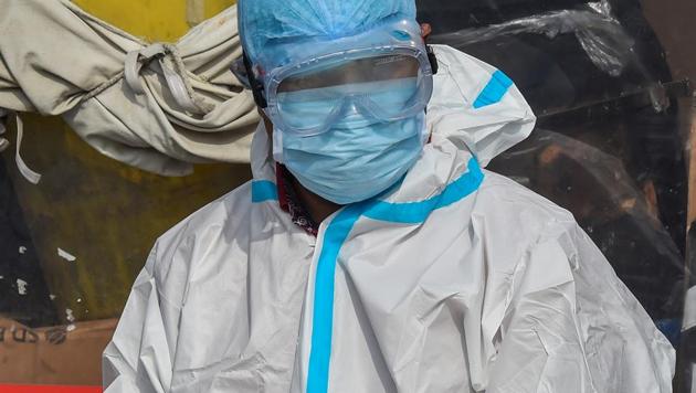 A health worker wearing protective gear prepares to collects swab samples for Covid-19 test at Baila Gaon Jhuggi Basti in New Delhi on Tuesday.(PTI Photo)
