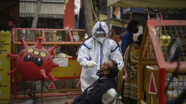 A medical worker in PPE kit collects a swab sample from a man to test for Covid-19 infection at Lajpat Nagar market in New Delhi.(Biplov Bhuyan/HT PHOTO)
