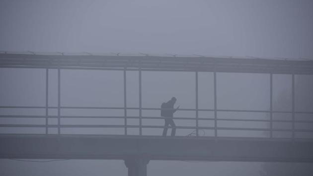 A person walks along a foot over bridge amid dense fog on a cold morning at Old Delhi road in Gurugram on December 16. A cold wave occurs in plains when the minimum temperature is 10 degrees Celsius or below and/or is 4.5 notches lesser than the season’s normal for two consecutive days. (Parveen Kumar / HT Photo) A person walks along a foot over bridge amid dense fog on a cold morning at Old Delhi road in Gurugram on December 16. A cold wave occurs in plains when the minimum temperature is 10 degrees Celsius or below and/or is 4.5 notches lesser than the season’s normal for two consecutive days. (Parveen Kumar / HT Photo)