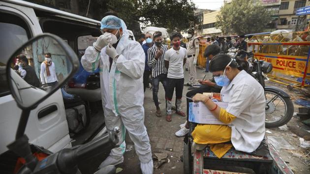 A health worker gets ready to take samples from people to test for Covid-19 as another registers them at a marketplace in New Delhi.(AP Photo)