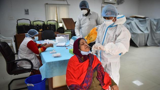 A health worker collects a swab sample to test for coronavirus infection in New Delhi on December 17. India has recorded the world’s second-highest number of infections behind the United States, but numbers have dipped steadily since hitting a peak in September. Daily cases were below 30,000 for the fifth straight day on December 18. (Sanchit Khanna / HT Photo)
