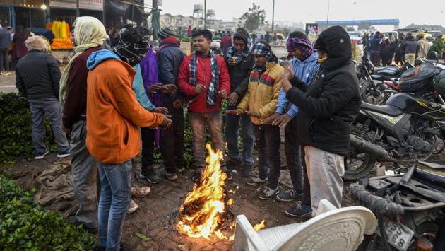 People warm themselves around a bonfire made using gunny bags on a cold winter morning at Ghazipur vegetable market in New Delhi on December 17. At 3,13,831 as on December 18, India’s active cases are less than 1/30th the amount of total recoveries made so far, the health ministry said. (Biplov Bhuyan / HT Photo)
