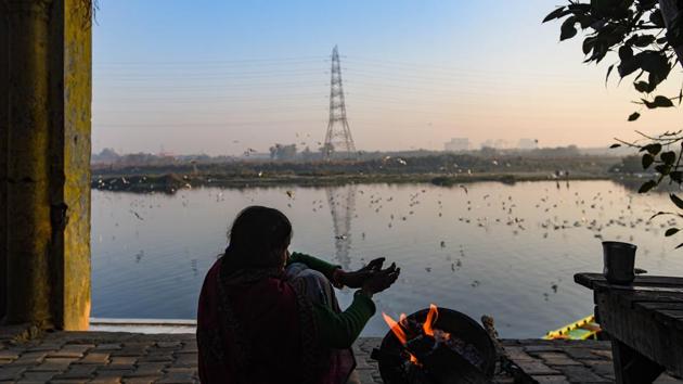 A woman warms herself around a bonfire amid cold weather, at Yamuna Ghat, in New Delhi. (Amal KS/HT PHOTO) A woman warms herself around a bonfire amid cold weather, at Yamuna Ghat, in New Delhi. (Amal KS/HT PHOTO)