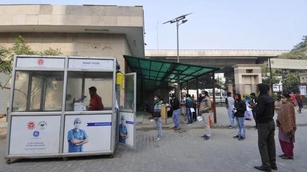 People queue outside a collection kiosk as a health worker collects swab samples at Sector 30 District Hospital in Noida on December 15. As cumulative cases of the respiratory disease close in on 10 million, the addition of 31,087 new discharges in the previous 24 hours has also taken the number of total recoveries past 9.5 million. (Sunil Ghosh / HT Photo)