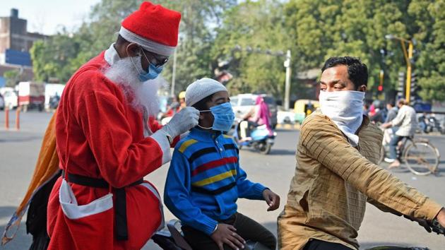 A social worker dressed as Santa Claus distributes face masks to commuters as part of an awareness campaign against the Covid-19 at a traffic junction in Ahmedabad on December 18. The pandemic has accelerated in the US and appears to have lost momentum in India, despite the country being home to some of the most crowded cities on the planet. (Sam Panthaky / AFP) 