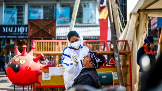 A health worker screens a shopper for Covid-19 at a makeshift testing booth in a market area in New Delhi on December 19. Total cases were 10.0 million, up just over 25,000 in the previous 24 hours, with 9.6 million recoveries and 145,136 deaths, according to the health ministry. In September, the country had been recording daily new cases of almost 100,000 and looked on track to surpass the United States as the worst-hit country. (Jewel Samad / AFP) 