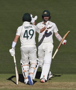 Australia's Joe Burns, right, is congratulated by teammate Steve Smith after hitting a 6 to win their cricket test match against India on the third day at the Adelaide Oval in Adelaide, Australia, Saturday, Dec. 19, 2020. (AP Photo/David Mariuz) (AP)
