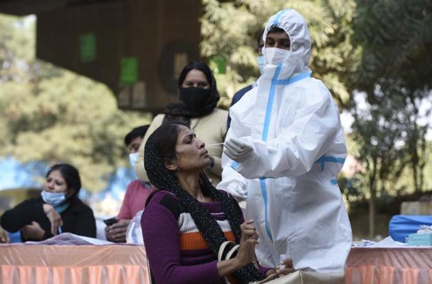 A medical worker in PPE coveralls collects a swab sample from a woman in Gurugram. (Parveen Kumar/HT) A medical worker in PPE coveralls collects a swab sample from a woman in Gurugram. (Parveen Kumar/HT)