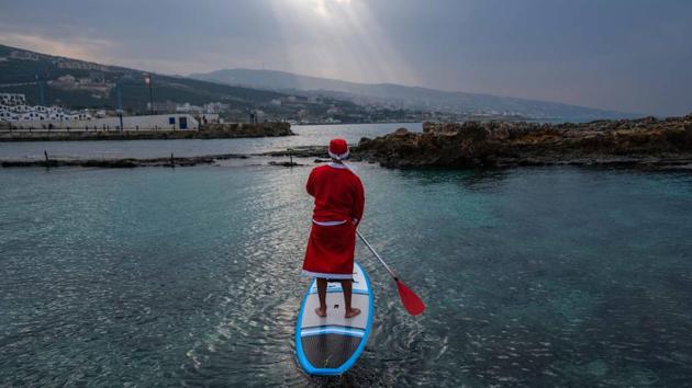 A man dressed in a Santa Claus outfit rides on a standup paddle in Batroun, Lebanon on December 22. (Ibrahim Chalhoub / AFP) A man dressed in a Santa Claus outfit rides on a standup paddle in Batroun, Lebanon on December 22. (Ibrahim Chalhoub / AFP)