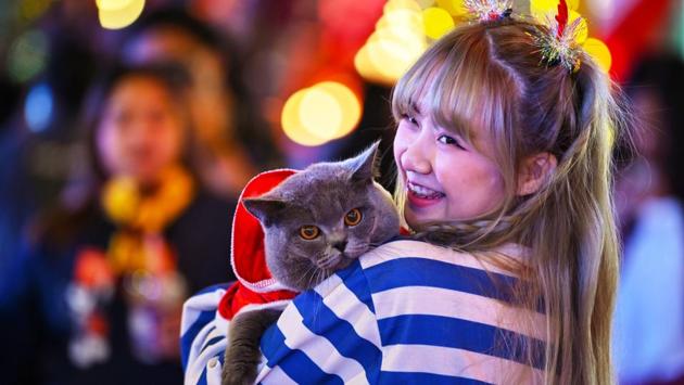 A woman poses with a cat dressed in a Santa Claus outfit outside a shopping mall in Bangkok, Thailand on December 22. Stricter rules have been introduced in Bangkok for the New Year, with organisers of celebrations told to seek official permission to hold gatherings. (Lillian Suwanrumpha / AFP) A woman poses with a cat dressed in a Santa Claus outfit outside a shopping mall in Bangkok, Thailand on December 22. Stricter rules have been introduced in Bangkok for the New Year, with organisers of celebrations told to seek official permission to hold gatherings. (Lillian Suwanrumpha / AFP)