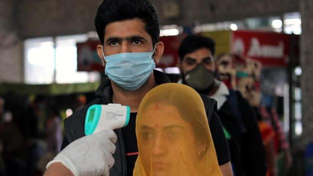 A health worker in personal protective equipment (PPE) checks the temperature of passengers amid the spread of the coronavirus disease at a railway station in Mumbai.(REUTERS) A health worker in personal protective equipment (PPE) checks the temperature of passengers amid the spread of the coronavirus disease at a railway station in Mumbai.(REUTERS)