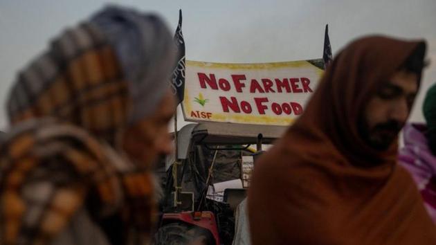 Farmers stand next to a fire as they warm themselves on a cold winter morning at the site of a protest against new farm laws, at Singhu border, near New Delhi. (REUTERS) Farmers stand next to a fire as they warm themselves on a cold winter morning at the site of a protest against new farm laws, at Singhu border, near New Delhi. (REUTERS)