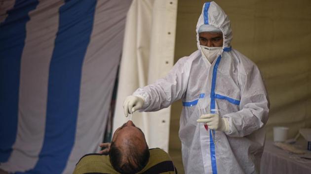 A health worker in PPE coveralls collects a swab sample from a person for coronavirus screening at a temporary testing facility in Sarai Kale Khan, New Delhi on December 23. A total of 1,46,756 deaths have been reported so far in the country among people who tested positive for the infection. The health ministry has stressed that more than 70% of the deaths occurred due to comorbidities. (Biplov Bhuyan / HT Photo) A health worker in PPE coveralls collects a swab sample from a person for coronavirus screening at a temporary testing facility in Sarai Kale Khan, New Delhi on December 23. A total of 1,46,756 deaths have been reported so far in the country among people who tested positive for the infection. The health ministry has stressed that more than 70% of the deaths occurred due to comorbidities. (Biplov Bhuyan / HT Photo)
