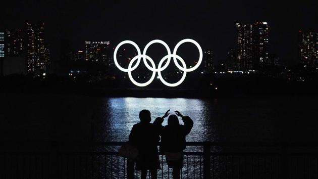 file photo of a man and a woman looking at the Olympic rings float in the water in the Odaiba section in Tokyo.(AP) file photo of a man and a woman looking at the Olympic rings float in the water in the Odaiba section in Tokyo.(AP)
