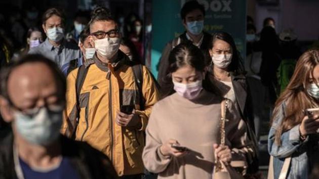 Pedestrians wearing protective masks walk on a footbridge in Hong Kong.(Bloomberg)