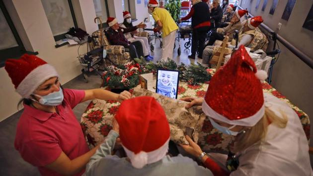 Pasqualina Ghilardi, 87, center, is flanked by carer Michela Valle, left, and director Maria Giulia Madaschi, as she talks on a video call with Caterina Damiano, a donor unrelated to her, who bought and sent her a sweater as Christmas present through an organization dubbed "Santa's Grandchildren", at the Mariano Zanchi nursing home in Alzano Lombardo, one of the area that most suffered the first wave of COVID-19, in northern Italy.(AP)