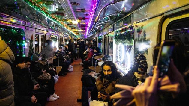 Commuters wearing face masks ride a metro train decorated with Christmas lights in Moscow, Russia on December 25. (Dimitar Dilkoff / AFP) Commuters wearing face masks ride a metro train decorated with Christmas lights in Moscow, Russia on December 25. (Dimitar Dilkoff / AFP)