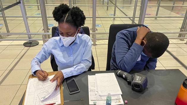 South African health ministry officials collect tracing forms from international travellers at OR Tambo airport on December 21. The check-in was effortless, Delay noted. There is no need to show proof of a Covid-19 test. There are no lines at security, where the big old X-ray machines have been replaced by a high-tech full-body scanner. Just a quick temperature check and turn in a tracking form to a health official. (Jerome Delay / AP)