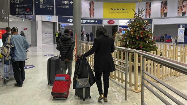 Arriving passengers walk by a Christmas tree at Paris Charles de Gaulle airport on December 22. For those whose final destination was Paris, passengers are triage for immigration, depending on their flight’s origin. Proof of a negative Covid-19 test was required here but social distances not necessarily observed. (Jerome Delay / AP)