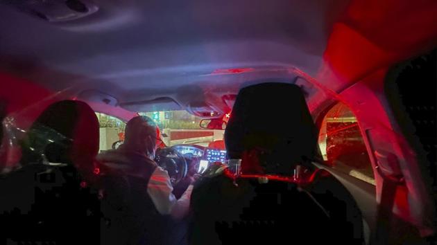 A taxi driver takes passengers to their destination in Paris after they arrived at Charles de Gaulle airport on December 22. Curbside, on a drizzling, dark morning, the cab driver remains inaudible, because of a thick plastic sheet separating him from the passengers. The curfew lifts over Paris as the clock strikes 6 a.m — the highways are packed again. (Jerome Delay / AP)