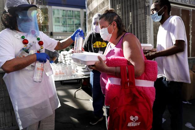 People receive a holiday-themed takeout meal from the Midnight Mission in Skid Row on Christmas day amid the Covid-19 pandemic on December 25, 2020 in Los Angeles, California. (AFP/Mario Tama) People receive a holiday-themed takeout meal from the Midnight Mission in Skid Row on Christmas day amid the Covid-19 pandemic on December 25, 2020 in Los Angeles, California. (AFP/Mario Tama)