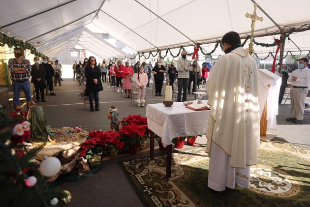 Father Rafael Saiz celebrates Christmas Mass outdoors at St. Mary's Catholic Church beneath a tent with social distancing due to the Covid-19 pandemic on December 25, 2020 in Los Angeles, California. California has become the first state to hit 2 million Covid-19 cases. Southern California remains at zero percent of its remaining ICU bed capacity amid a spike in coronavirus cases and hospitalizations. (AFP/Mario Tama) Father Rafael Saiz celebrates Christmas Mass outdoors at St. Mary's Catholic Church beneath a tent with social distancing due to the Covid-19 pandemic on December 25, 2020 in Los Angeles, California. California has become the first state to hit 2 million Covid-19 cases. Southern California remains at zero percent of its remaining ICU bed capacity amid a spike in coronavirus cases and hospitalizations. (AFP/Mario Tama)