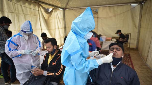 Health workers in PPE coveralls collect swab samples for Covid-19 tests at Anand Vihar Bus Terminal in New Delhi on December 26. Continuing the trend of the decreasing number of Covid-19 infections, Delhi on December 27 recorded 655 fresh Covid-19 cases, the capital’s lowest in over four months. (Sanchit Khanna / HT Photo) Health workers in PPE coveralls collect swab samples for Covid-19 tests at Anand Vihar Bus Terminal in New Delhi on December 26. Continuing the trend of the decreasing number of Covid-19 infections, Delhi on December 27 recorded 655 fresh Covid-19 cases, the capital’s lowest in over four months. (Sanchit Khanna / HT Photo)