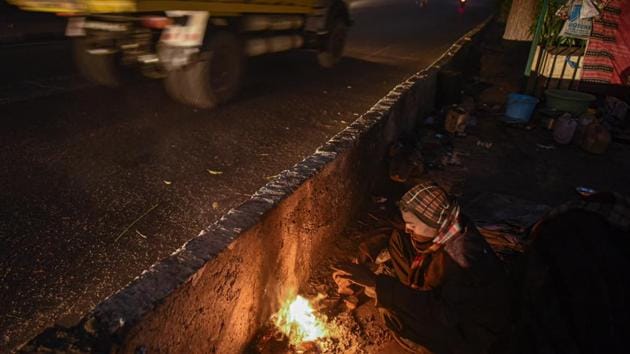 A man warms himself by a small fire on a cold winter morning at Nizamuddin in New Delhi on December 24. No significant change in minimum and maximum temperatures is likely during the weekend. They are likely to rise by 2-5°C in minimum temperatures briefly and fall by 2-5°C in maximum temperatures over north-western India during subsequent three days, IMD said on December 25. (Biplov Bhuyan / HT Photo)
