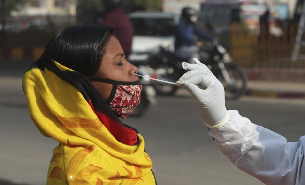 A health worker takes nasal swab sample of a woman to test for COVID-19 in Jammu.(AP)