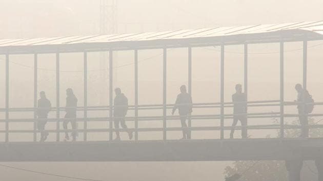 Commuters crossing a foot over bridge amid dense fog on a cold winter day, at IFFCO Chowk in Gurugram on December 24. North-western India, including Delhi, Noida and Ghaziabad, mostly recorded “very poor” to “severe” air quality on December 25 amid a drop in wind speed that has slowed down the dispersal of pollutants. (PTI)